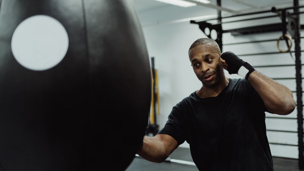 Boxer practicing punches on a heavy bag in a gym environment.